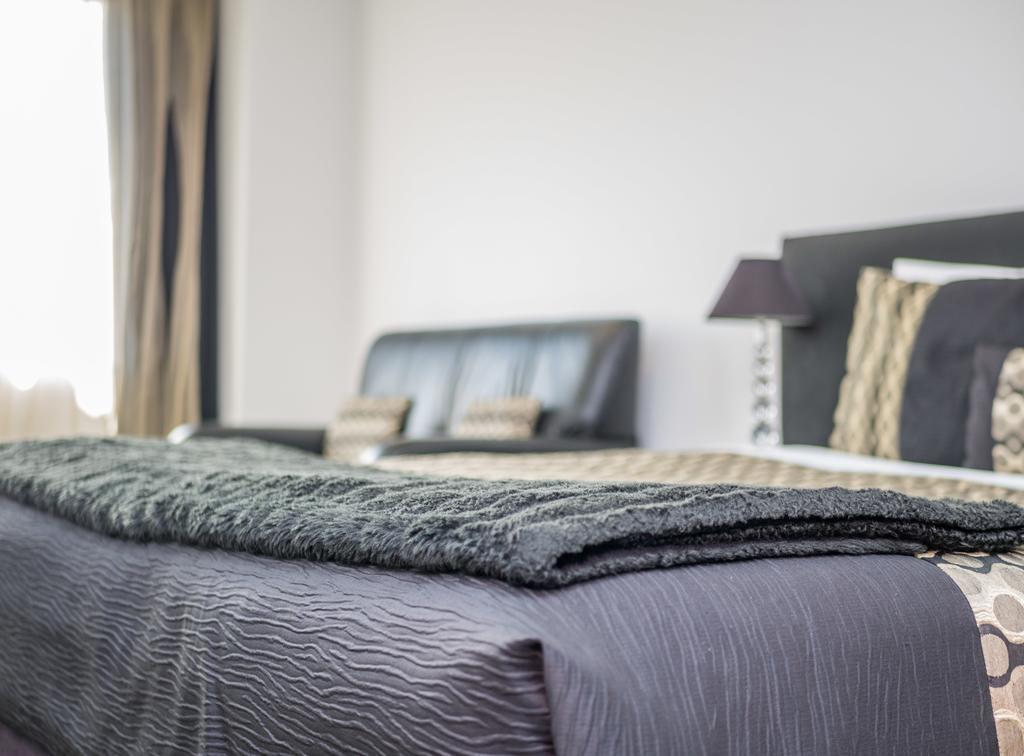 Bellano Motel Suites Christchurch Ngoại thất bức ảnh A bed with a throw